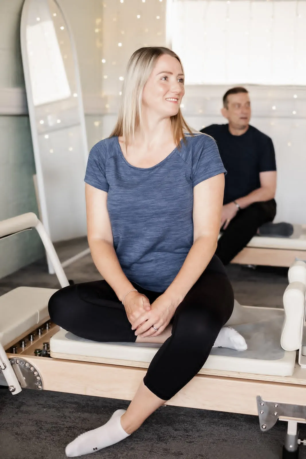 Smiling client sitting on a Reformer at Pilates Flow Reformer in Quedgeley